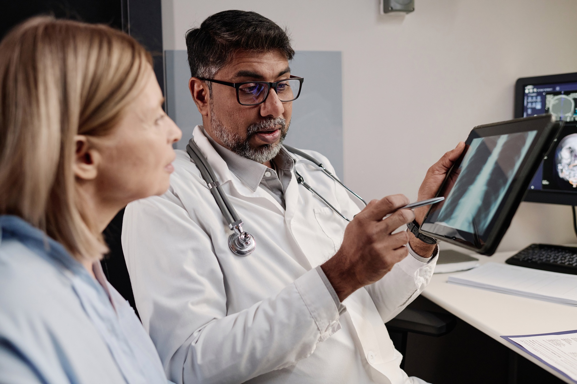 Doctor Showing X-ray Image On Digital Tablet To Patient