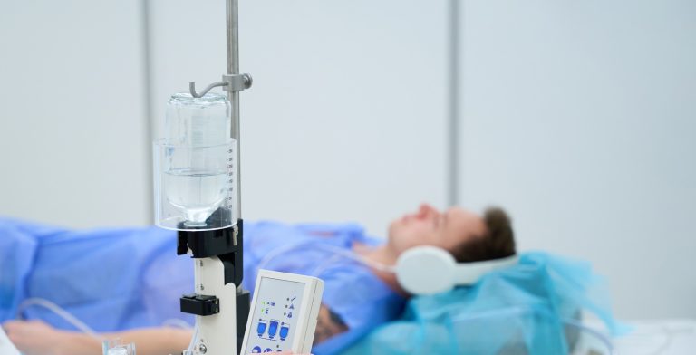 Technologist preparing man for contrast-enhanced lower extremity joint MRI